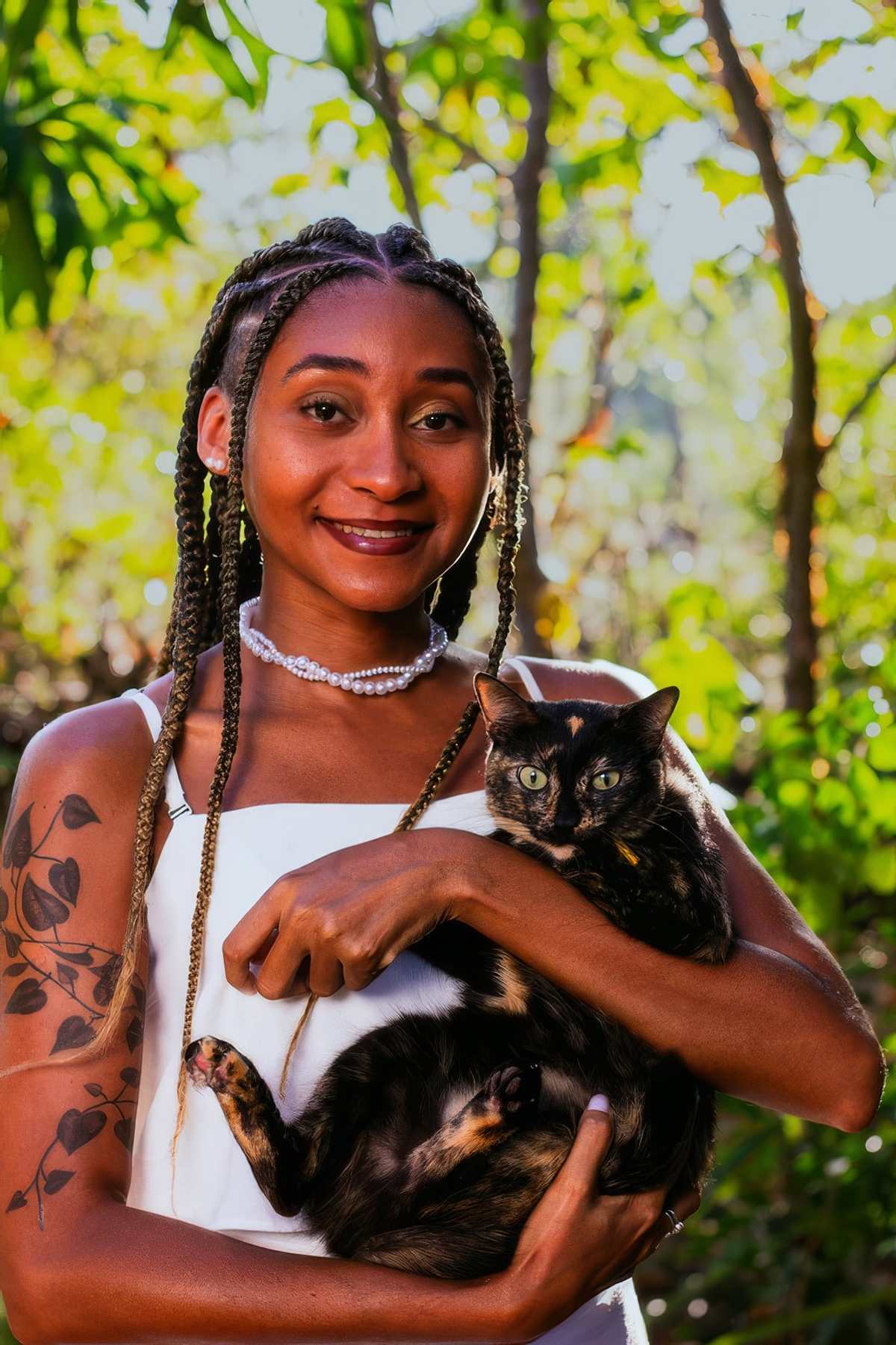 Bruna com uma gata no colo, de vestido branco, no quintal