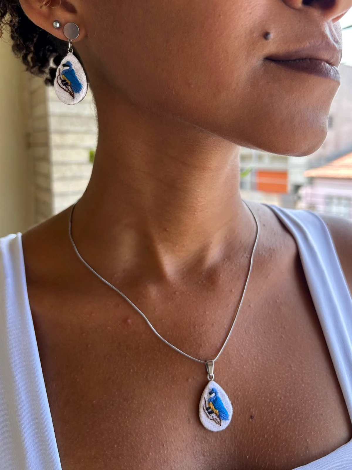 Colar Asas do Horizonte com pingente em gota bordado em azul, na modelo